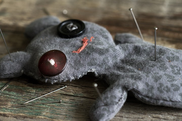 Voodoo doll and pins on old vintage wooden floor
