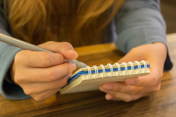 female hands with pen writing on notebook