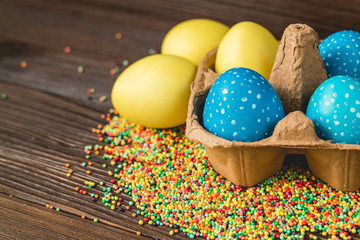 Yellow and blue easter eggs in a box on a wooden table