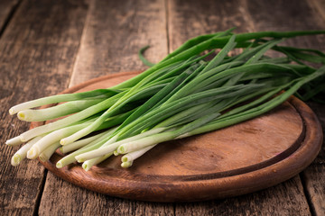Spring onions also known as salad onions, green onions or scallions on wood background
