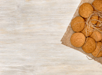 Fototapeta na wymiar Oatmeal cookies on the burlap on white wooden background