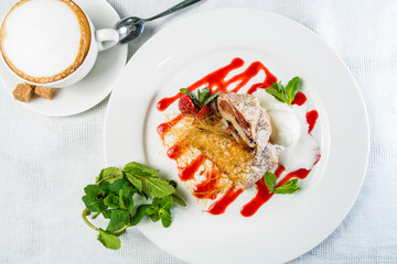 Tasty strudel with ice-cream and mint leaves on plate