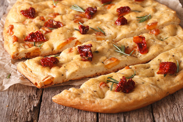 Tasty Italian focaccia with dried tomatoes close up on the table. horizontal

