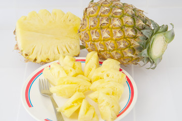 Pineapple slices in plate with fork on white background