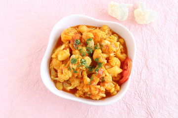 Indian vegetarian food cauliflower curry, which is a side dish for items like chapati, in a white ceramic tray.