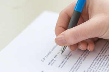 Close Up View of a woman`s  hand filling employment agreement form.