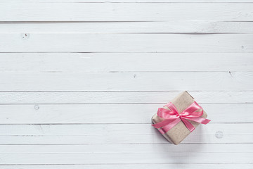 Gift box with pink ribbon on white painted wooden planks and emp