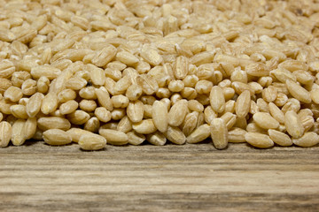 Grain of pearl Barley on a wooden background.