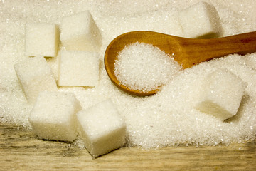 Sugar and wooden spoon on wooden background