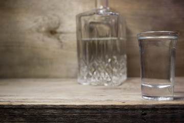 A glass of vodka on wooden table.