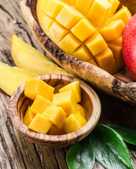 Mango fruit and mango cubes on the wooden table.