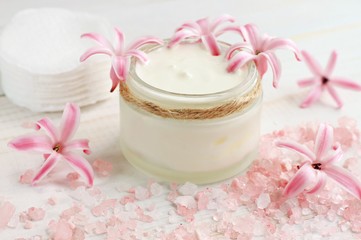 Obraz na płótnie Canvas Fresh skin care cream, flowers, pink bath salt, cotton pads. Natural beauty treatment.