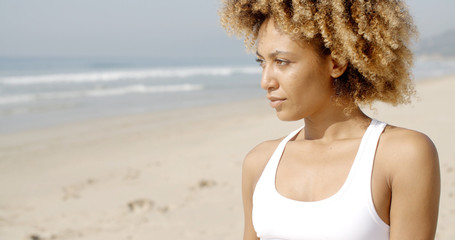 African woman wearing a white bikini tanning on the beach