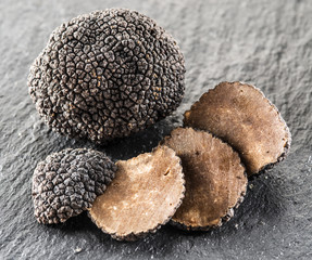 Black truffles and truffle slices on the graphite board. - obrazy, fototapety, plakaty