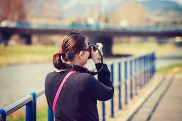 Portrait of female tourist holding camera and taking photos