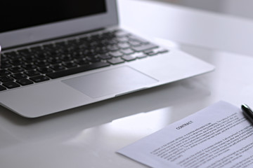 .Office workplace with a laptop and contract document on the light reflecting table