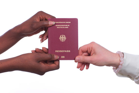 Afrikanische und europäische Hände halten deutschen Reisepass isoliert