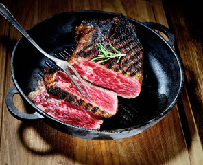 fried steak in a frying pan on a wooden surface
