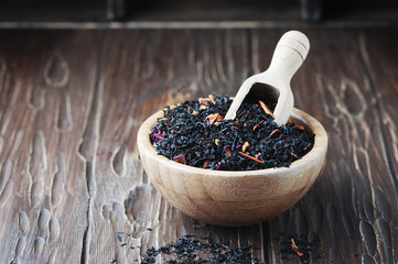 Delicious black tea with petals on the wooden table