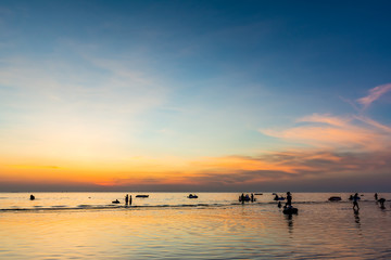 Naklejka na ściany i meble Beautiful sunset at sea beach and people silhouette.