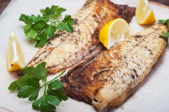 Grilled fish with herbs and lemon on rustic background