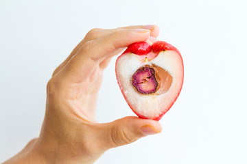 A rose apple, cut in half, held in the hand of a young woman, isolated on white.