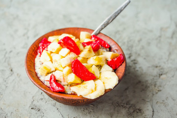 oatmeal with banana and strawberry in a clay plate