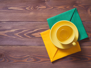 Coffee cup with yellow and green napkins on the wooden table. Top view