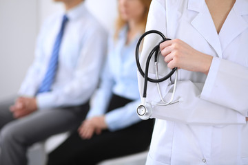 Doctor holding a stethoscope in his hands , the patient on the background