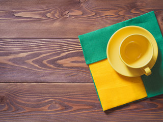 Coffee cup with yellow and green napkins on the wooden table. Top view