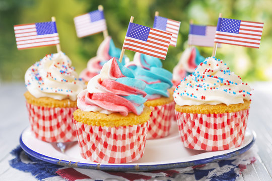 Cupcakes with red-white-and-blue frosting and American flags on