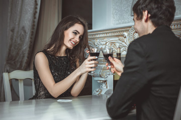 Beautiful young couple with glasses of red wine in luxury restaurant