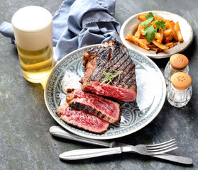 fried steak on a plate, chips, beer on a dark background
