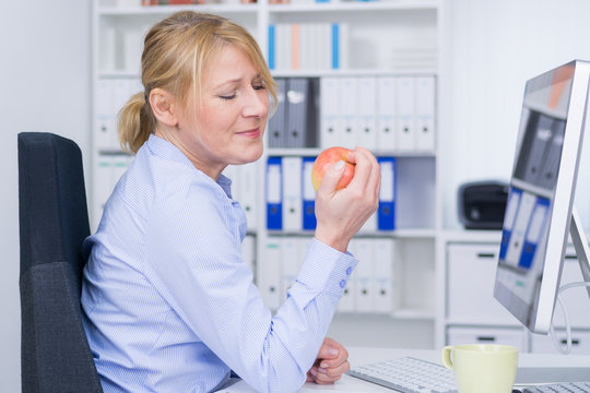 frau vor dem coputer genie&szlig;t apfel