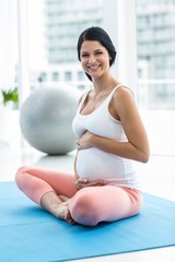 Fototapeta na wymiar Pregnant woman touching her stomach while exercising