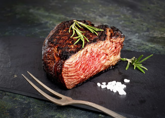 veal steak marbled basalt, a knife for meat, rosemary on a dark background