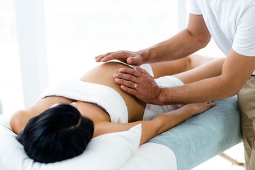 Obraz na płótnie Canvas Pregnant woman receiving a stomach massage from masseur