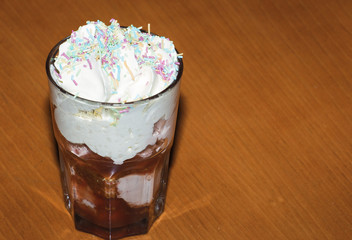 Dessert, chocolate ice cream in a glass. Fresh ice cream in a glass cup covered with whipped cream and sprinkled with icing. 
