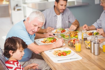 Grandfather assisting grandson while having breakfast