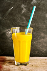 Mango beverage in a tall glass with a straw