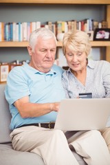 Senior couple using laptop while sitting on sofa