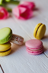 A beautiful bouquet of pink tulips with colorful macaroons on white wooden background