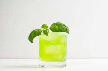 Summer cocktail with basil leaf on the white wooden background