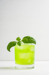 Summer cocktail with basil leaf on the white wooden background