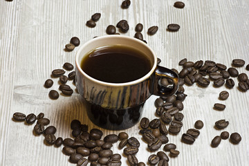 Cup of coffee with scattered roasted coffee beans