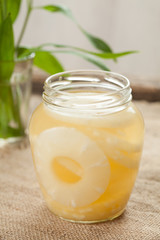 Sliced pineapple rings with juice in glass on vintage cloth background