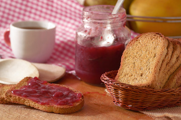Some toasted bread slices with some marmalade spread. Wooden table in a rustic kitchen.