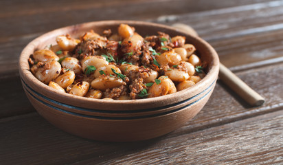 beans with meat and tomato sauce on the wooden table