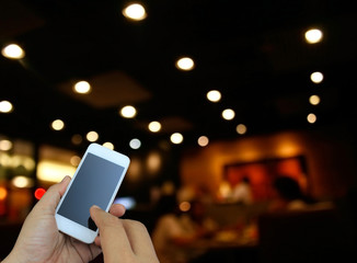 hand holding the smartphone on blur restaurant background