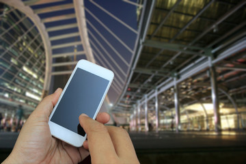 hand holding the smartphone on blur of business area , buildings